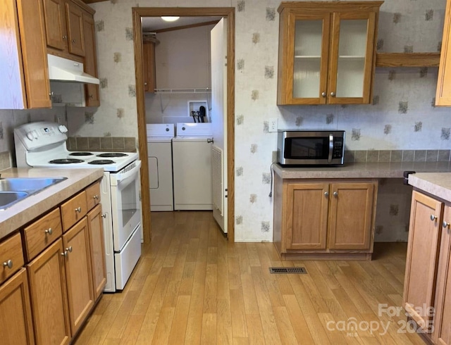 kitchen featuring wallpapered walls, white range with electric stovetop, stainless steel microwave, and separate washer and dryer