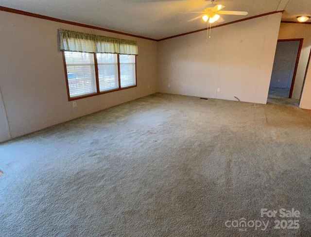 empty room with ceiling fan, carpet flooring, and crown molding