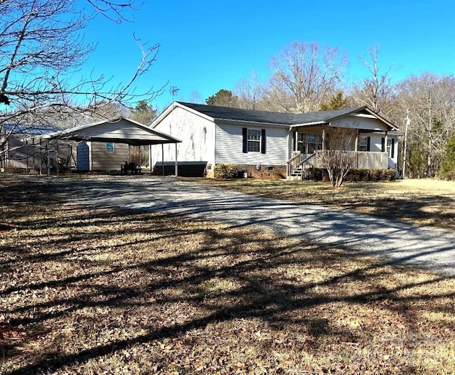 single story home featuring covered porch, crawl space, gravel driveway, and a detached carport