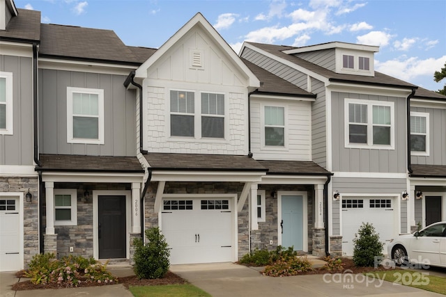 multi unit property with board and batten siding, stone siding, driveway, and an attached garage