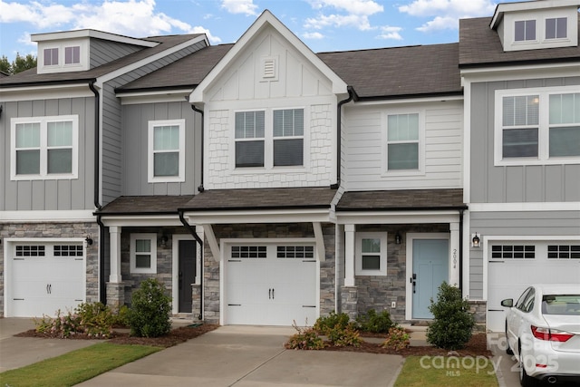 multi unit property with a garage, stone siding, driveway, and board and batten siding