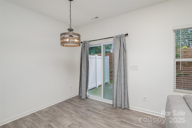 empty room featuring light wood-style floors, baseboards, and visible vents