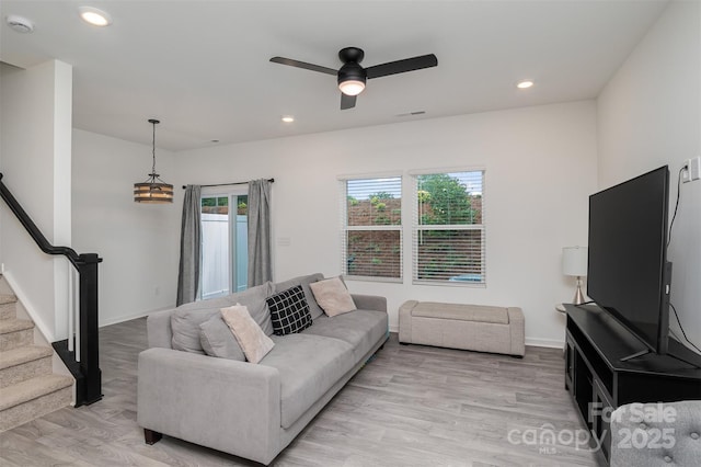 living area featuring baseboards, visible vents, stairs, light wood-style floors, and recessed lighting