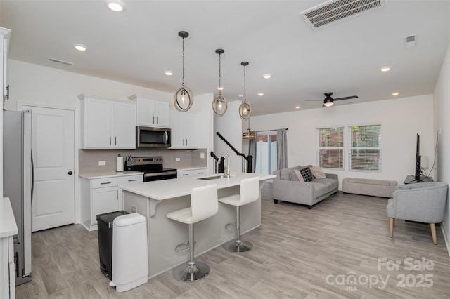 kitchen with light countertops, visible vents, appliances with stainless steel finishes, open floor plan, and a sink