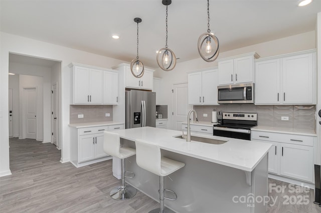 kitchen featuring a breakfast bar area, stainless steel appliances, a sink, and light countertops