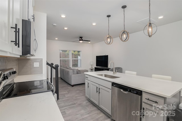 kitchen featuring light wood finished floors, appliances with stainless steel finishes, a kitchen island with sink, light countertops, and a sink