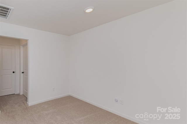 empty room featuring baseboards, visible vents, and light colored carpet