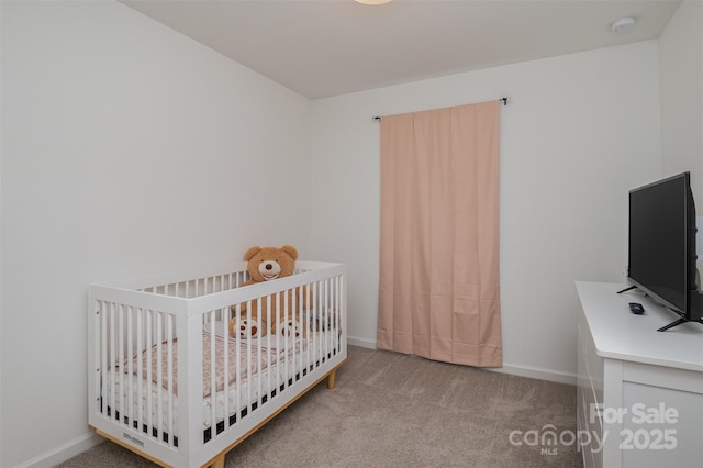 carpeted bedroom with a crib and baseboards