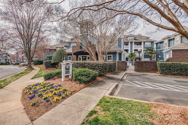 exterior space with curbs, a gate, sidewalks, and a residential view