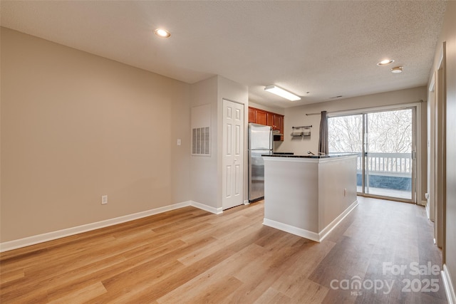 kitchen with visible vents, light wood finished floors, freestanding refrigerator, and baseboards