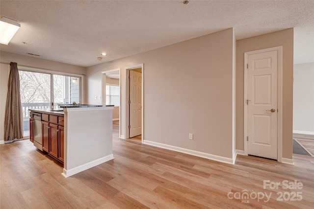 kitchen with light wood-style floors, a textured ceiling, baseboards, and dishwasher