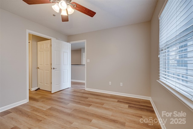 unfurnished bedroom featuring ceiling fan, light wood-type flooring, and baseboards