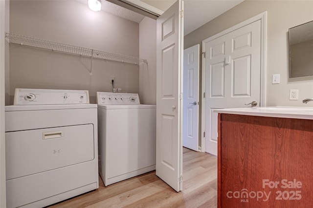 clothes washing area with laundry area, light wood-style floors, and independent washer and dryer