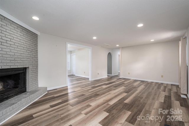 unfurnished living room featuring baseboards, a fireplace, wood finished floors, and recessed lighting