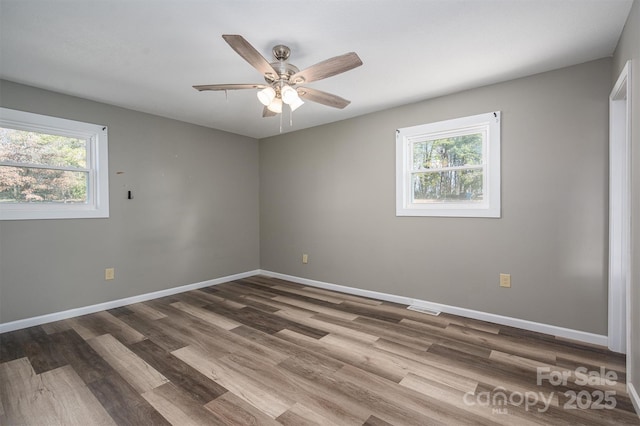 unfurnished room with plenty of natural light, baseboards, and wood finished floors