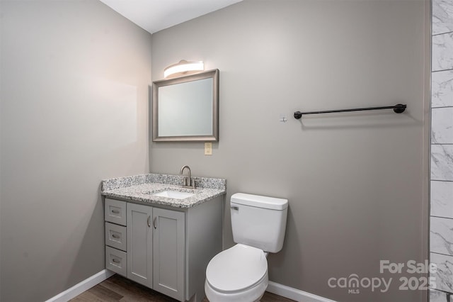 bathroom featuring toilet, vanity, and baseboards
