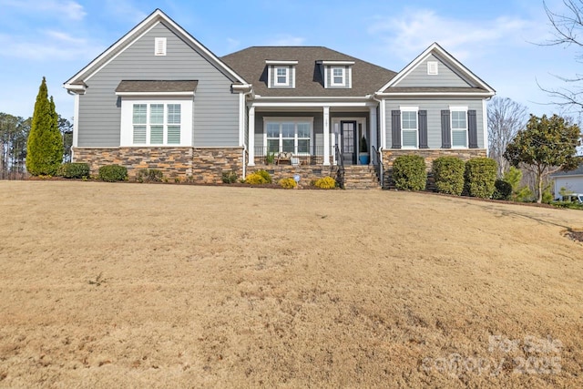 craftsman house with stone siding, covered porch, and roof with shingles