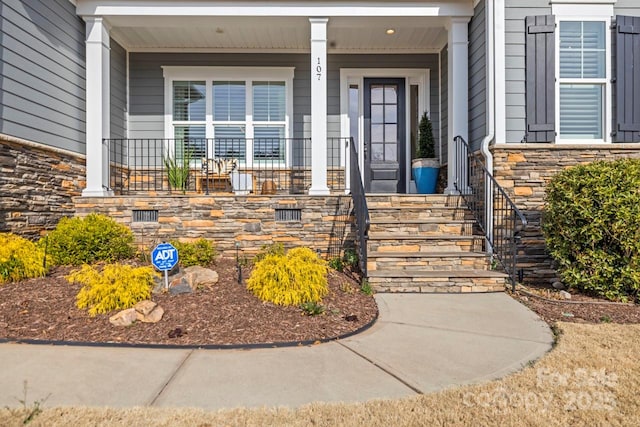 view of exterior entry with a porch and stone siding