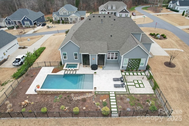 exterior space featuring a fenced in pool, roof with shingles, a fenced backyard, an in ground hot tub, and a patio