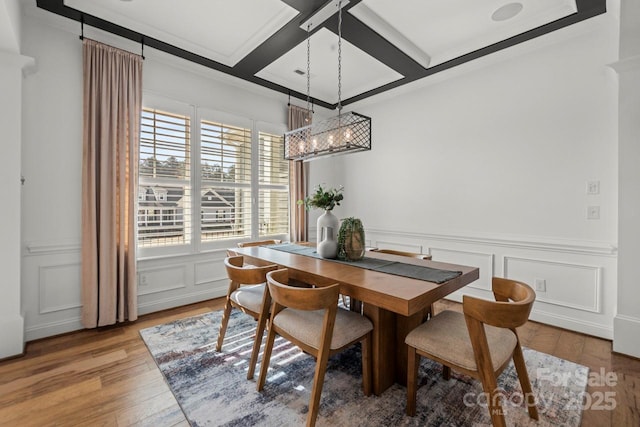 dining space with beamed ceiling, coffered ceiling, an inviting chandelier, light wood-style floors, and a decorative wall