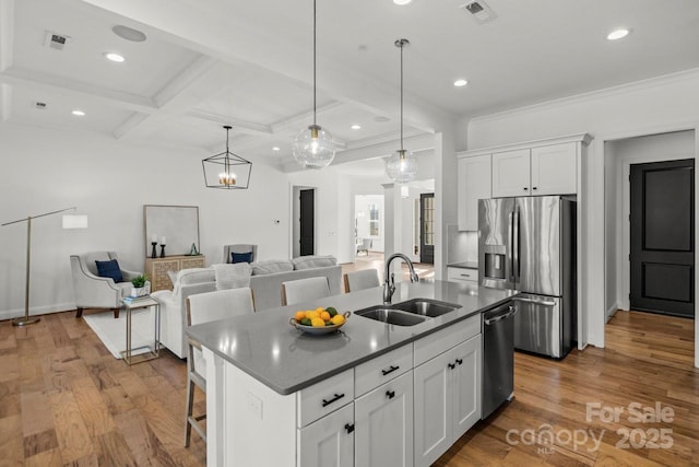 kitchen with a sink, coffered ceiling, wood finished floors, white cabinetry, and stainless steel appliances