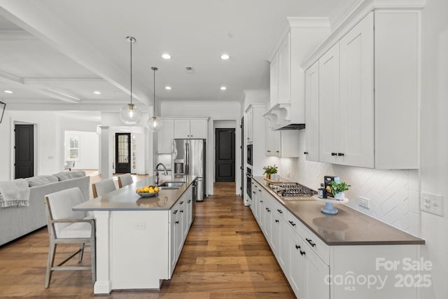 kitchen with a breakfast bar, a sink, appliances with stainless steel finishes, open floor plan, and backsplash