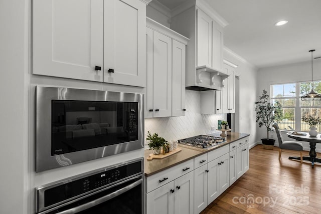 kitchen featuring dark wood finished floors, white cabinets, backsplash, and stainless steel appliances