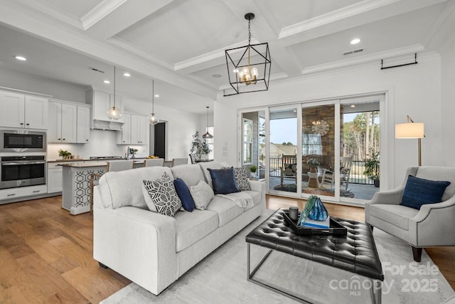 living room with beamed ceiling, wood finished floors, visible vents, and a chandelier