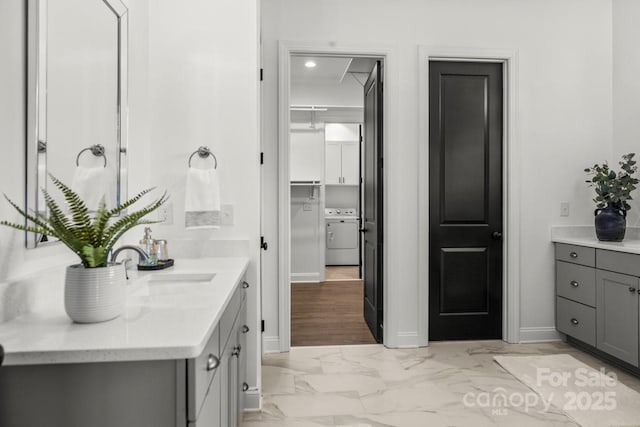 bathroom with vanity, washer / dryer, baseboards, and marble finish floor