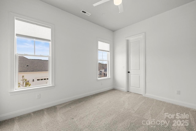 empty room featuring carpet flooring, baseboards, visible vents, and plenty of natural light