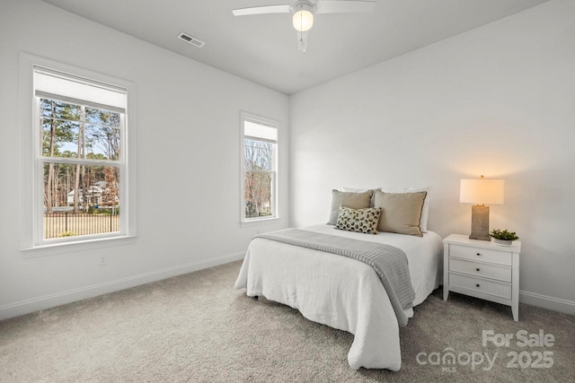 carpeted bedroom with visible vents, baseboards, and a ceiling fan