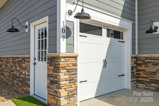 doorway to property with stone siding and a garage