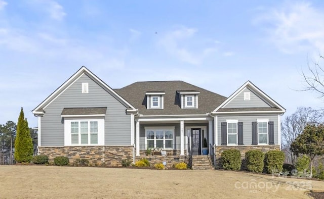 craftsman-style house featuring stone siding and roof with shingles