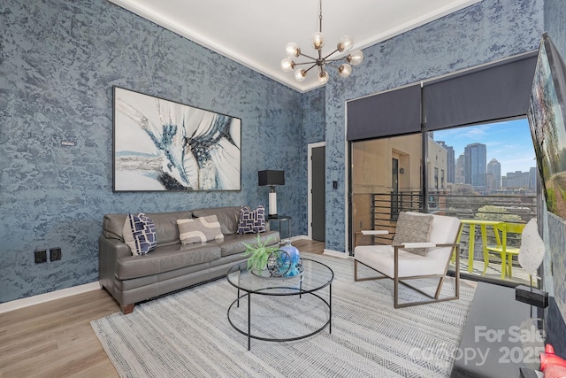 living area featuring an inviting chandelier, a city view, wood finished floors, and wallpapered walls