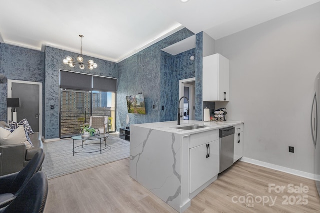 kitchen with wallpapered walls, light stone countertops, dishwasher, light wood-style flooring, and a sink