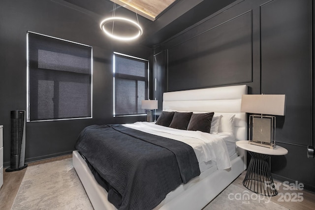 bedroom featuring a decorative wall and wood finished floors