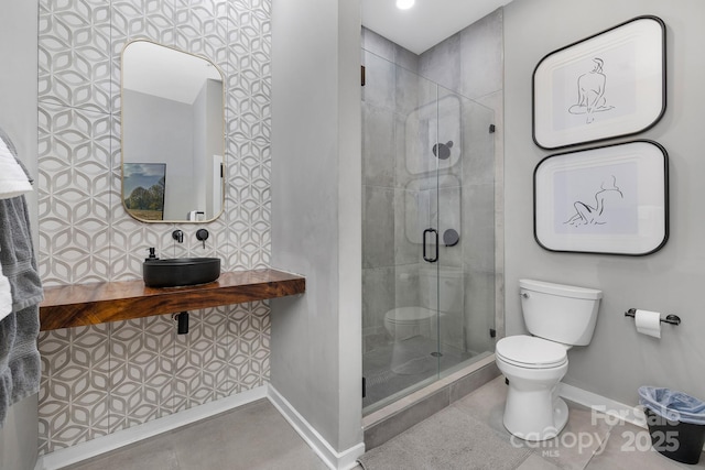 bathroom with a shower stall, toilet, baseboards, and tile patterned floors