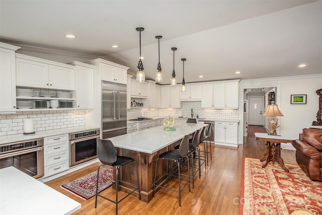 kitchen featuring stainless steel appliances, a breakfast bar area, light countertops, and white cabinetry