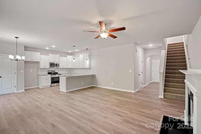 kitchen with ceiling fan with notable chandelier, stainless steel appliances, a peninsula, open floor plan, and light wood-type flooring