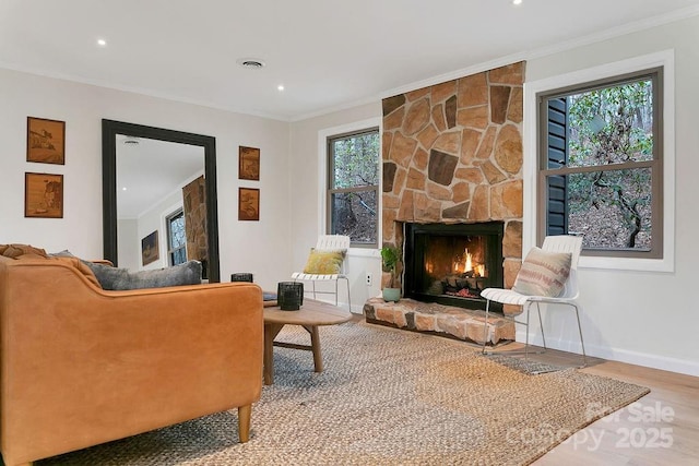 sitting room featuring baseboards, ornamental molding, wood finished floors, and a stone fireplace