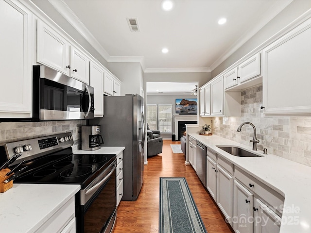 kitchen with visible vents, appliances with stainless steel finishes, light wood-type flooring, white cabinetry, and a sink