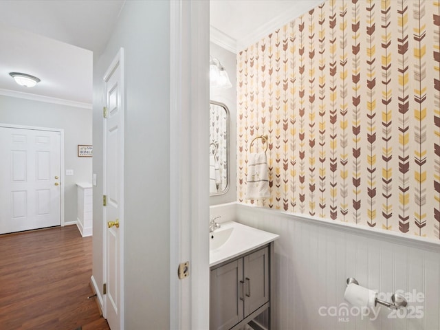 bathroom with ornamental molding, wainscoting, vanity, and wood finished floors