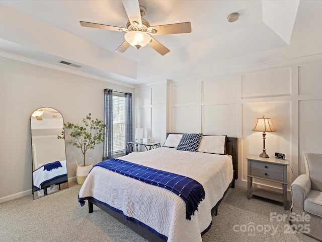 bedroom with light carpet, a tray ceiling, and a decorative wall