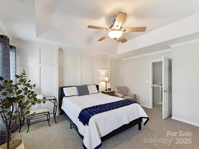 bedroom with a decorative wall, light carpet, baseboards, ornamental molding, and a tray ceiling