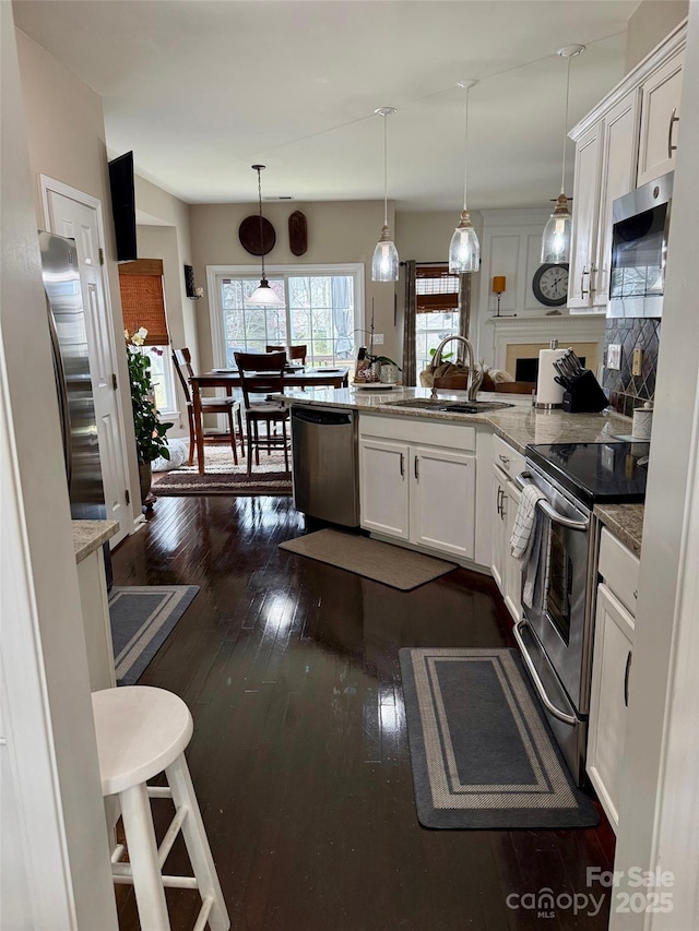 kitchen with white cabinets, a peninsula, stainless steel appliances, and a sink