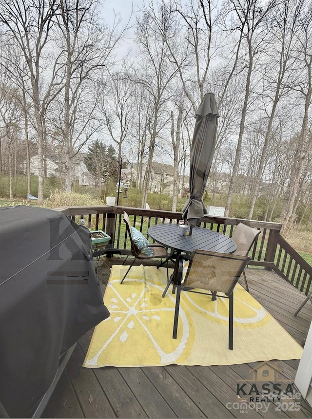 wooden terrace with outdoor dining area and a grill