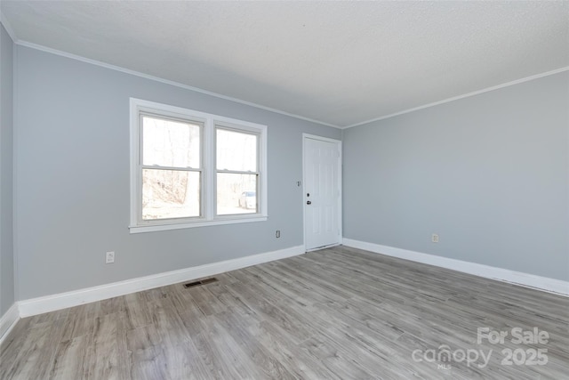 unfurnished room featuring visible vents, crown molding, baseboards, and wood finished floors