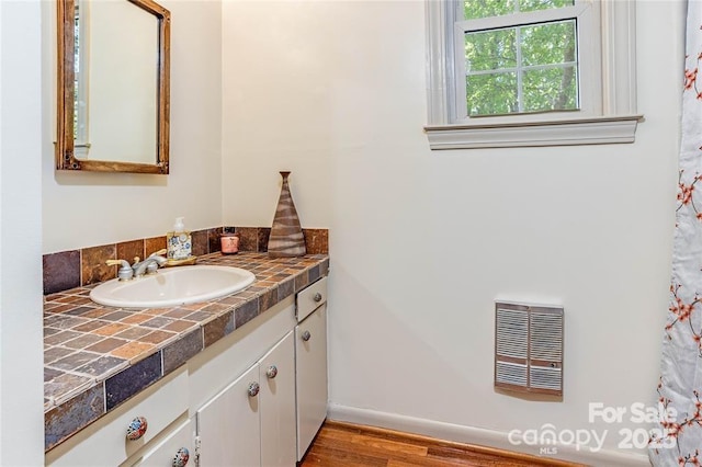 bathroom featuring baseboards, visible vents, wood finished floors, heating unit, and vanity