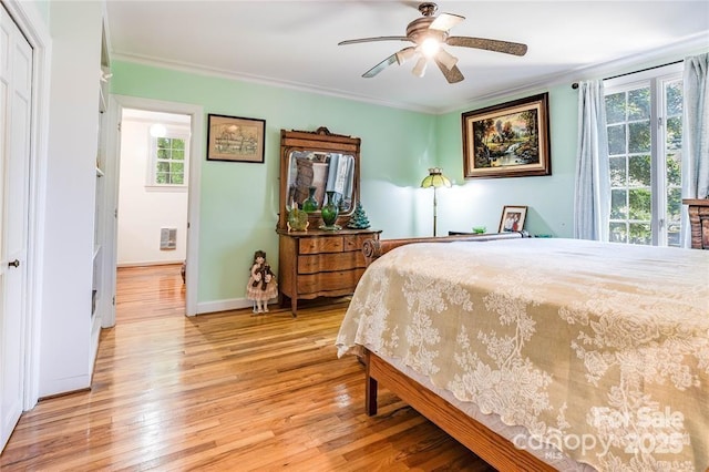 bedroom with light wood-type flooring, ceiling fan, baseboards, and crown molding