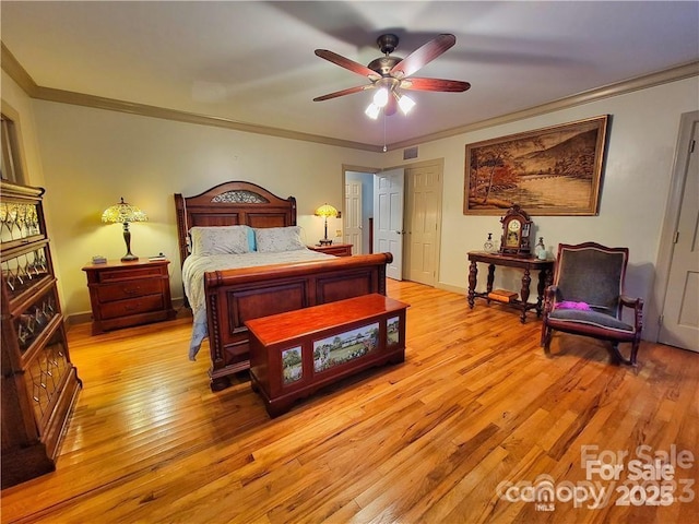 bedroom featuring a ceiling fan, baseboards, visible vents, light wood finished floors, and crown molding